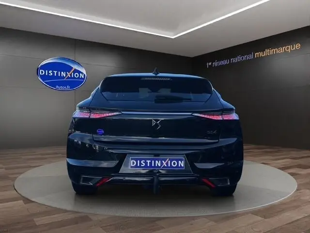 Vue arrière d'une DS4 noire 2022 avec spoiler de coffre, feux LED étirés et logo DS bien visible en showroom.