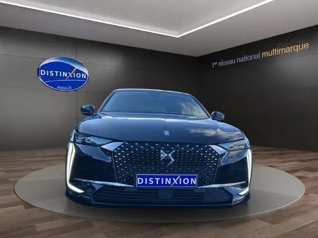 Vue avant d'une DS4 BleuHDi 130 Rivoli noire avec calandre distinctive et feux LED verticaux allumés dans un showroom.