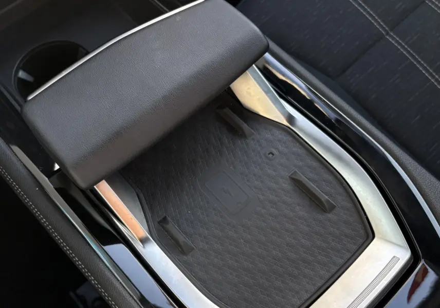 Gros plan sur le chargeur sans fil et accoudoir central noir dans l’habitacle du Renault Austral E-Tech blanc nacré.