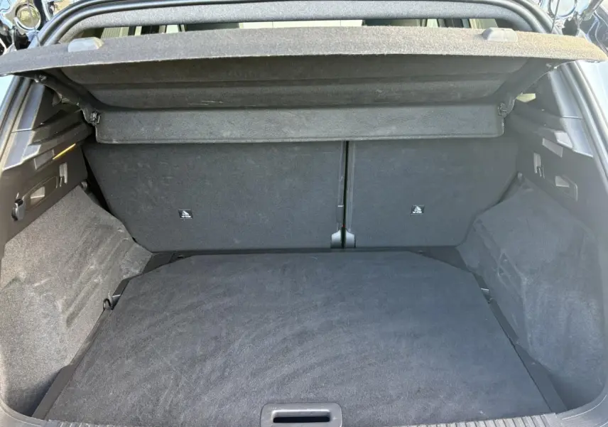 Vue intérieure du coffre ouvert du Renault Austral E-Tech, montrant un espace de rangement propre et tapissé de tissu noir.