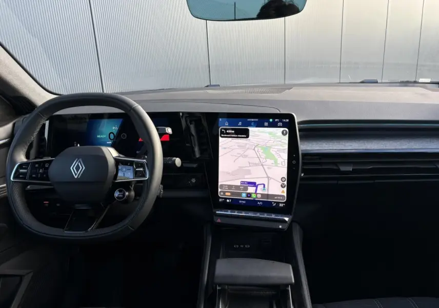 Vue intérieure frontale du tableau de bord du Renault Austral blanc nacré, avec écran tactile vertical affichant la navigation.