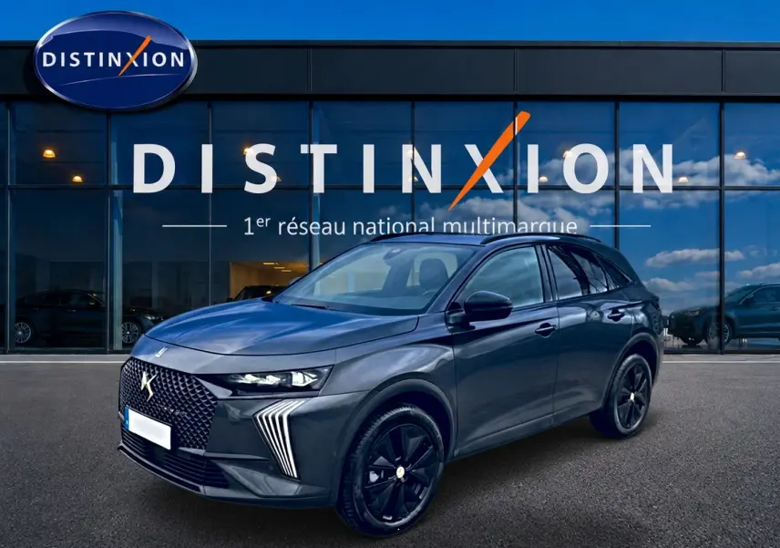 DS7 1.5 BlueHDi 130 gris titane en 3/4 avant droit, avec calandre distinctive et jantes noires brillantes.