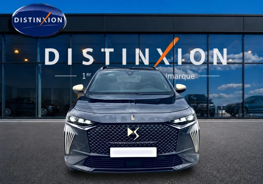 Vue de face du DS7 gris titane 2026 avec calandre distinctive et phares LED fins, devant une vitrine Distinxion.