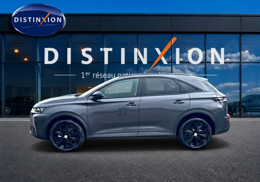 Vue profil droit du DS7 gris titane 2026 avec jantes noires, devant une vitrine Distinxion.