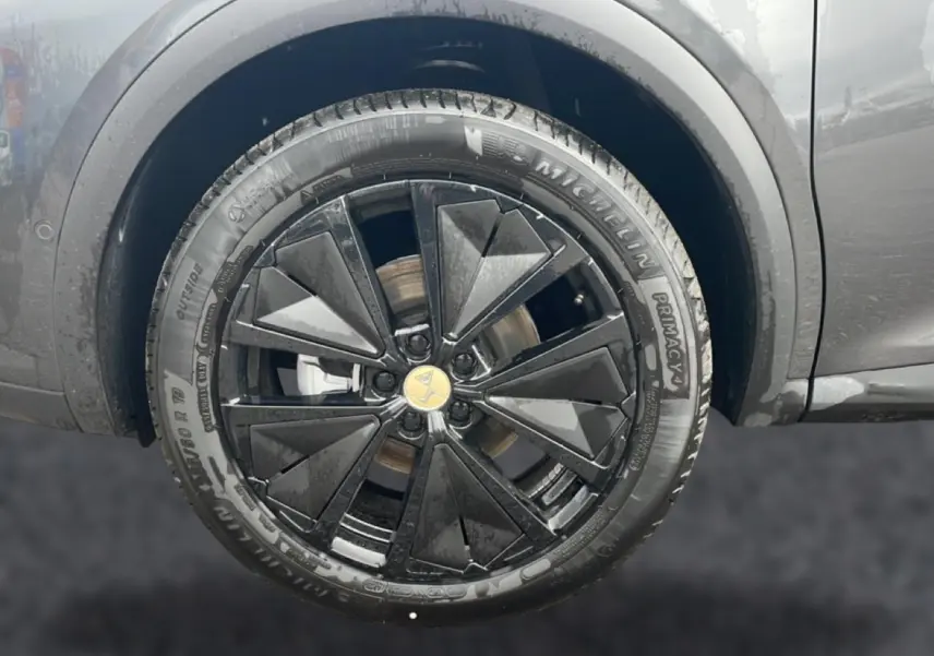 Gros plan sur la roue avant gauche du DS7 gris titane avec jante alu noire au design géométrique.