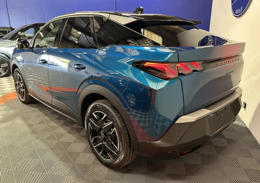 Vue 3/4 arrière droite d’un Peugeot 3008 III HYBRID bleu obsession avec attelage et jantes noires en showroom.