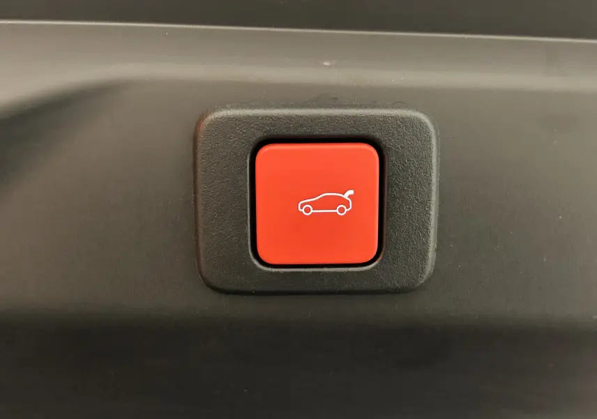 Gros plan sur le bouton rouge d'ouverture électrique du coffre dans l'habitacle du Peugeot 3008 Bleu Obsession.