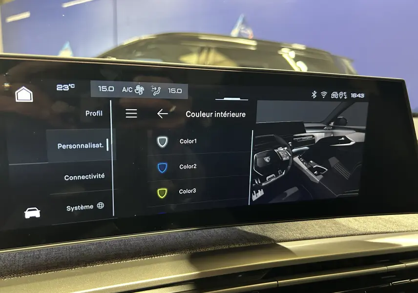 Écran tactile intérieur du Peugeot 3008 III Hybrid 145, affichant les options de personnalisation de couleur, avec reflet d’un véhicule bleu en arrière-plan.