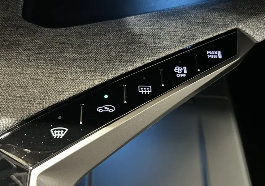 Gros plan sur les commandes tactiles de la climatisation du Peugeot 3008 III Hybrid, avec éclairage blanc et vert.