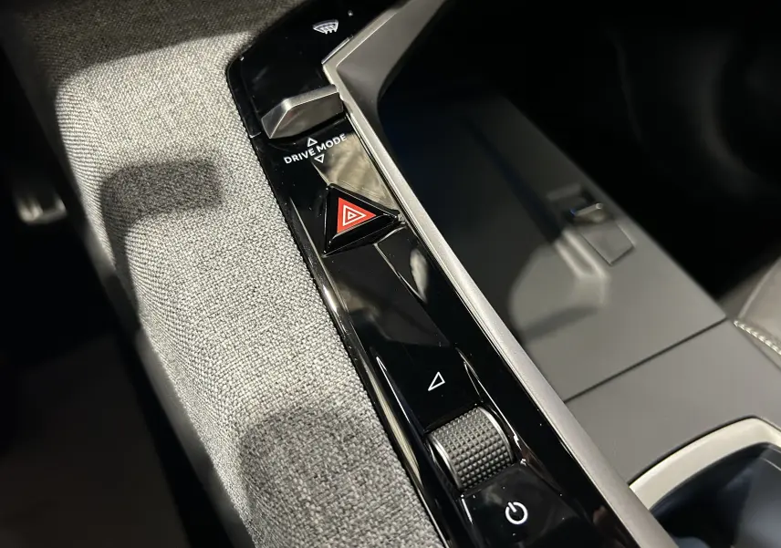 Gros plan sur la console centrale intérieure du Peugeot 3008 III Hybrid avec bouton de mode de conduite et signal d’alerte.
