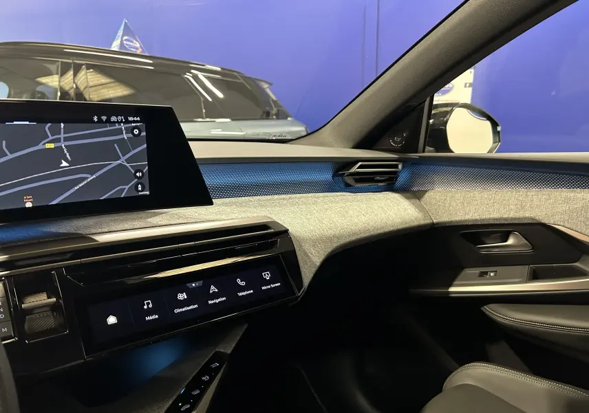 Vue intérieure côté passager du Peugeot 3008 III Hybrid 145 GT, avec tableau de bord moderne et éclairage bleu Obsession.
