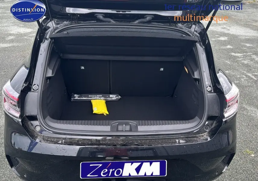 Coffre ouvert vu de l'arrière d'une Renault Clio V noire étoile avec intérieur de coffre vide et objets de sécurité.