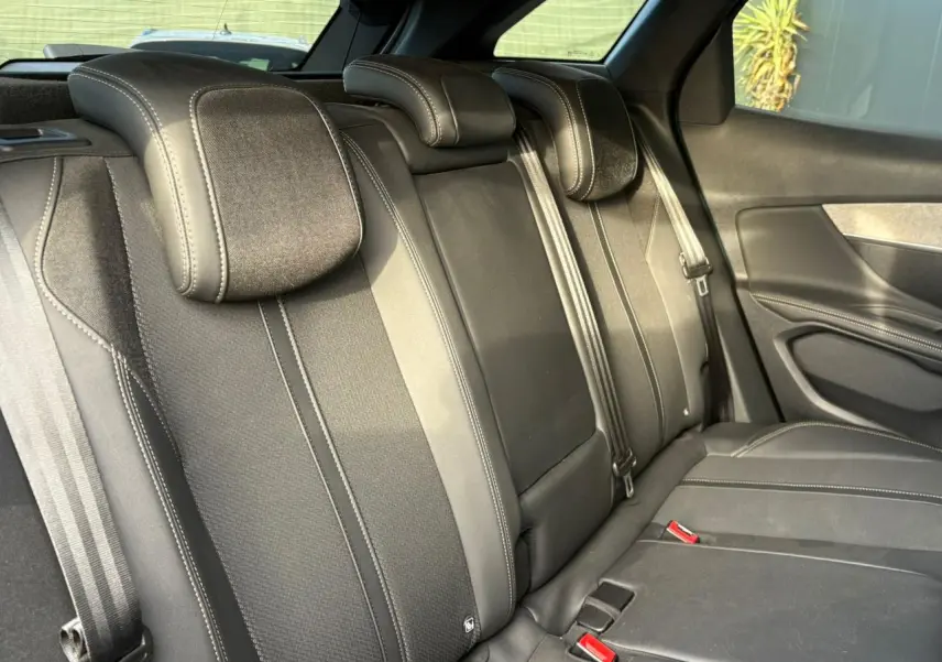 Vue intérieure de la banquette arrière noire du Peugeot 3008 2023 avec ceintures et appuie-têtes intégrés.