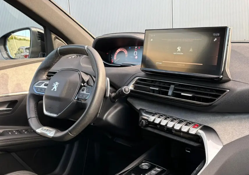 Intérieur avant droit du Peugeot 3008 GT 2023, volant cuir perforé et écran tactile 10 pouces allumé.
