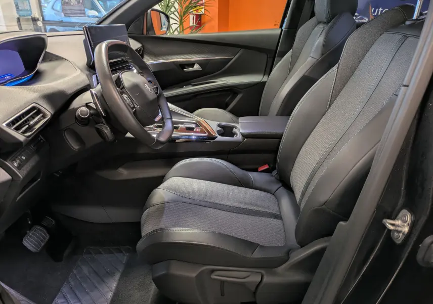 Vue intérieure côté conducteur du Peugeot 5008 noir 2024, mettant en valeur la sellerie TEP et tissu et le volant cuir.