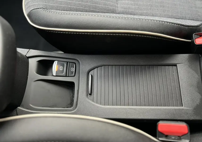 Vue rapprochée de la console centrale noire avec frein de parking électrique et accoudoir coulissant de la Renault Clio Rouge Désir.