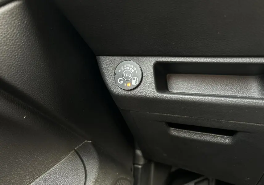 Gros plan sur le bouton de contrôle GPL noir dans l’habitacle de la Renault Clio Rouge Désir.
