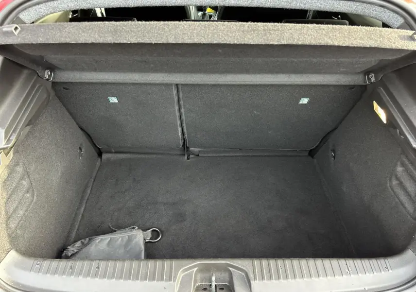 Coffre ouvert de la Renault Clio Rouge Désir 2025, vue intérieure montrant l'espace de rangement vide et tapis noir.