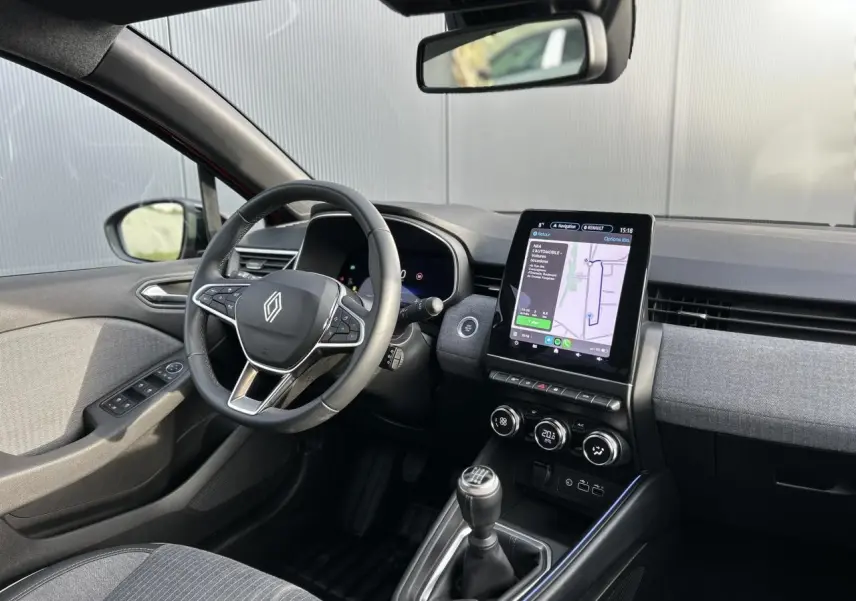 Vue intérieure côté conducteur de la Renault Clio 2025 avec tableau de bord moderne et écran tactile vertical GPS.