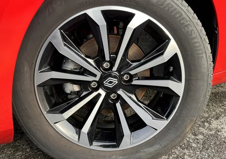 Gros plan sur la jante alliage diamantée 16" noire et argentée d'une Renault Clio Rouge Désir.