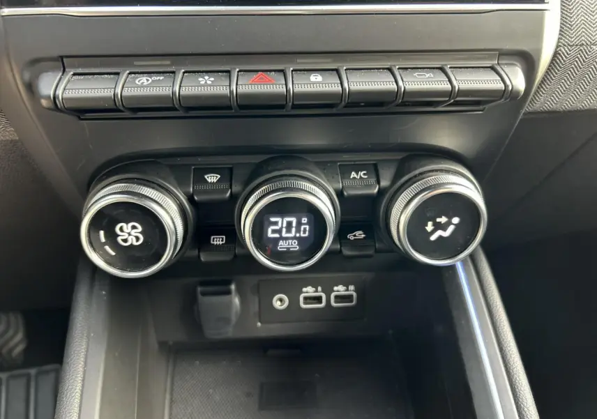 Gros plan sur la console centrale de la Renault Clio 2025, boutons de climatisation et ports USB visibles.