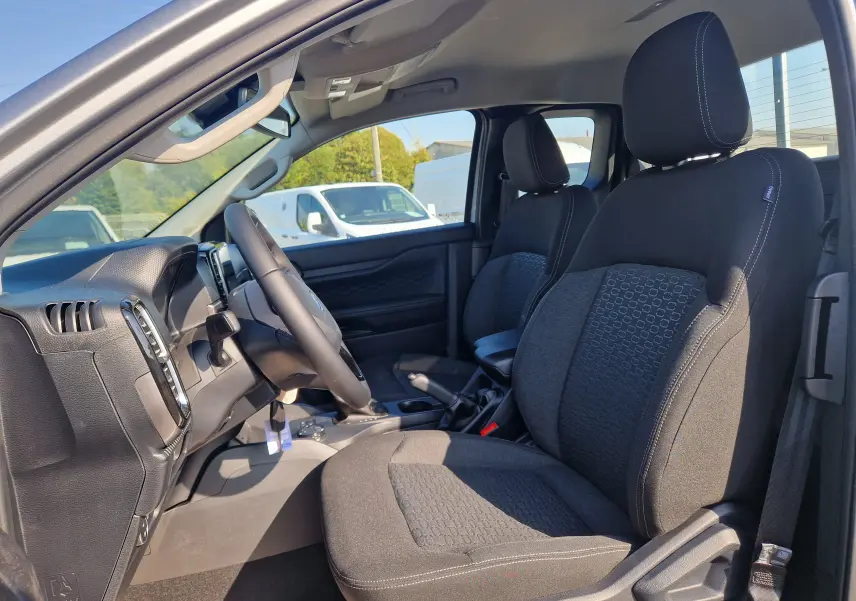 Intérieur avant droit du Ford Ranger Super Cabine 2026, sièges tissu noirs avec coutures contrastées, volant multifonction visible.