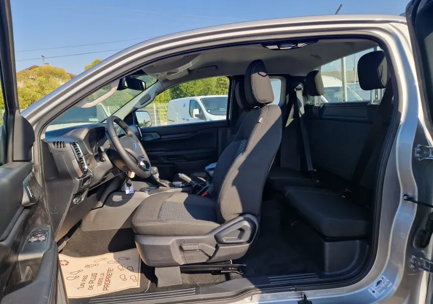 Vue intérieure côté gauche du Ford Ranger Super Cabine gris Iconic 2026, montrant les sièges avant et arrière ainsi que le tableau de bord.