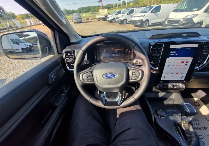 Vue intérieure côté conducteur du Ford Ranger Super Cabine gris Iconic, mettant en valeur le volant multifonction et l'écran tactile central.