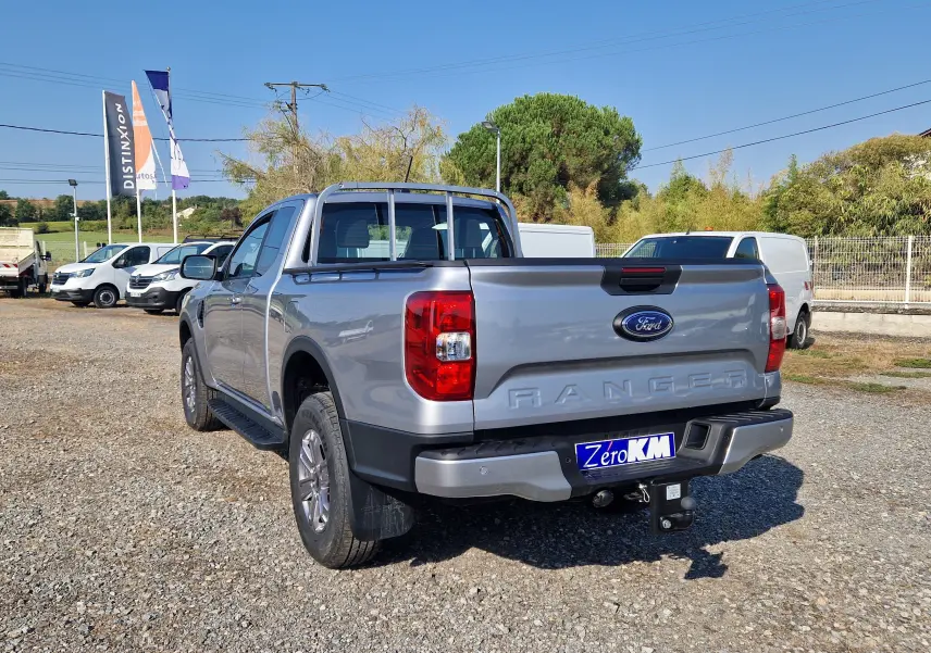 Ford Ranger Super Cabine gris Iconic vu en 3/4 arrière droit, avec attelage et barres de protection sur la benne.