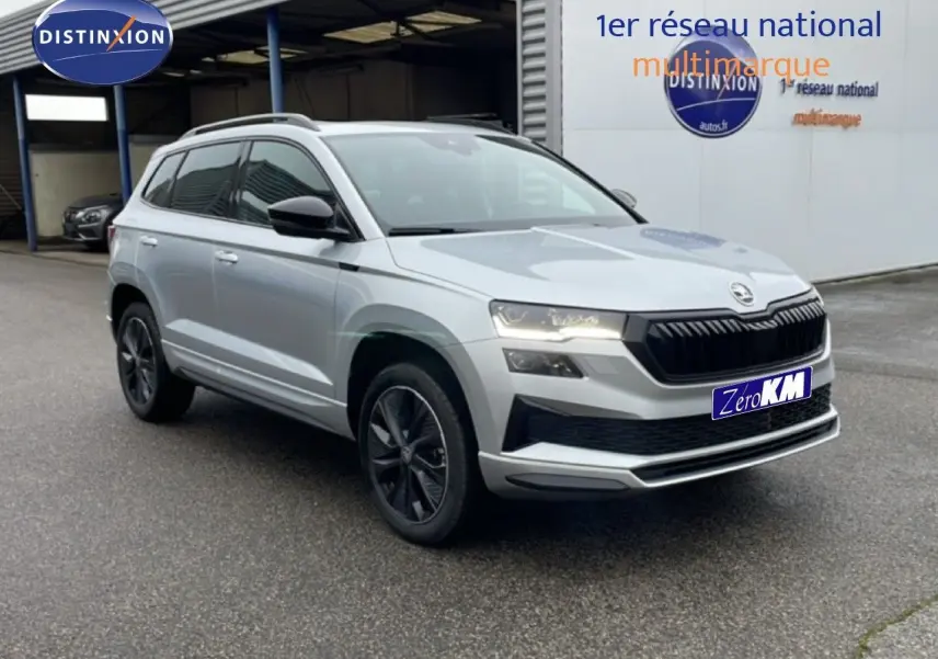 Vue 3/4 avant d'un Skoda Karoq gris argent métallisé avec jantes noires et calandre noire distinctive.