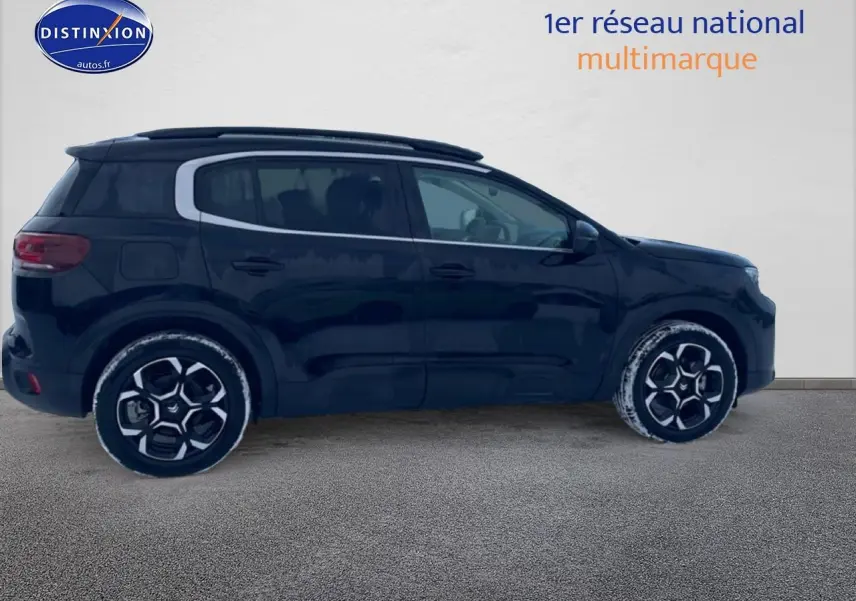 Profil droit d'un Citroën C5 Aircross noir 2025 avec jantes alu et barres de toit visibles sur fond clair.