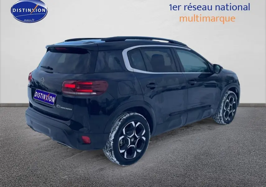 Vue 3/4 arrière droite d'un Citroën C5 Aircross noir avec jantes alu et barres de toit visibles.