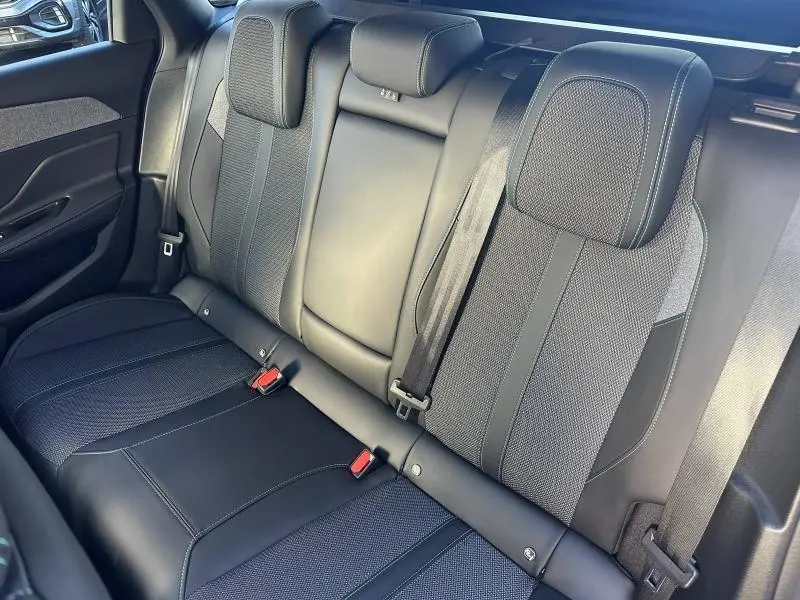 Vue intérieure des sièges arrière en cuir noir et tissu gris du Peugeot 308 SW 2024, avec ceintures de sécurité visibles.
