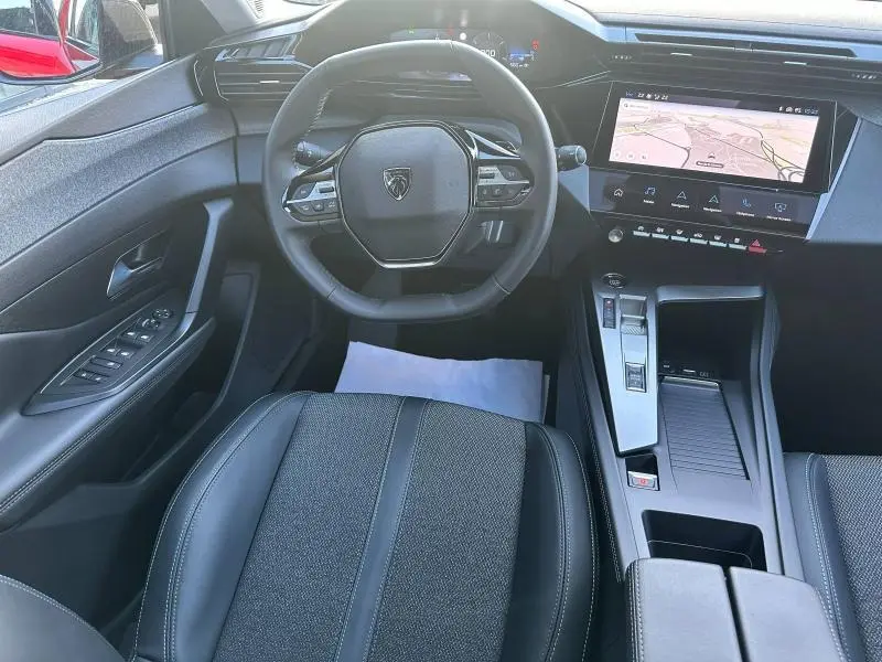 Vue intérieure centrée sur le volant et la console centrale du Peugeot 308 SW 2024, avec écran tactile et sellerie noire.