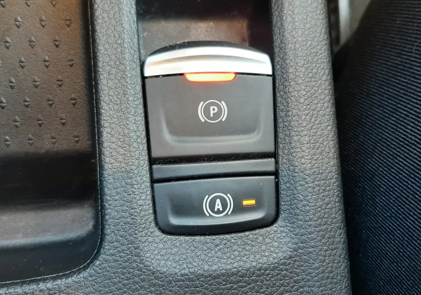 Gros plan sur les commandes de frein à main électrique et d’aide au démarrage sur Renault Captur E-Tech blanc nacré.
