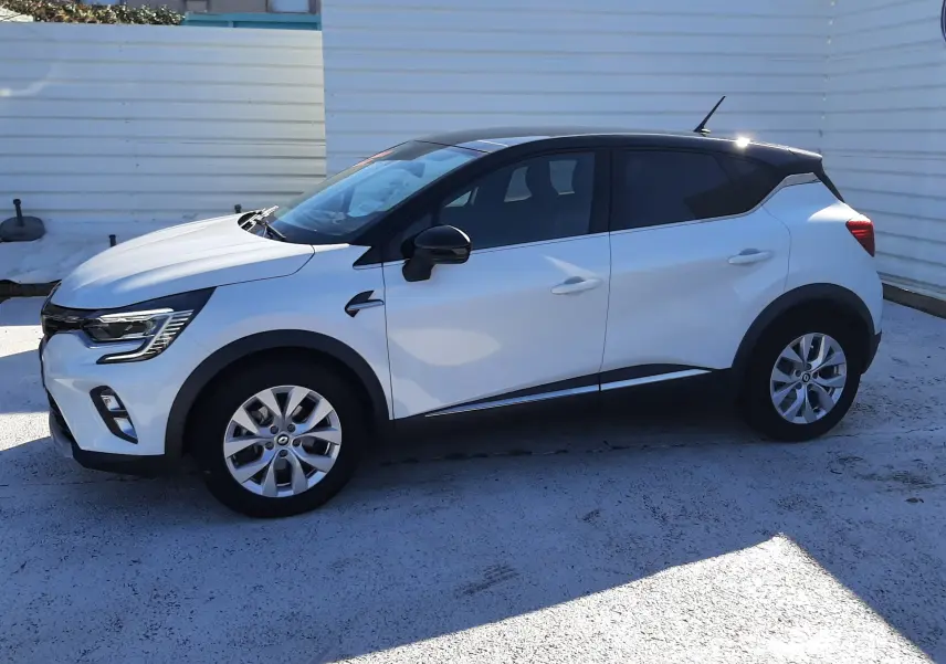 Renault Captur E-Tech 145ch Intens 2022 blanc nacré avec toit noir, vue de profil côté gauche en extérieur.