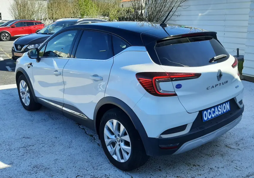 Vue 3/4 arrière droite du Renault Captur E-Tech blanc nacré avec toit noir et feux arrière LED distinctifs.
