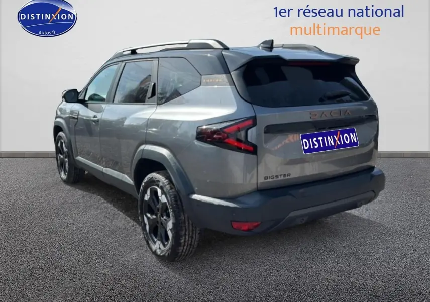 Vue 3/4 arrière droite du Dacia Bigster gris schiste avec barres de toit et jantes alu noires.