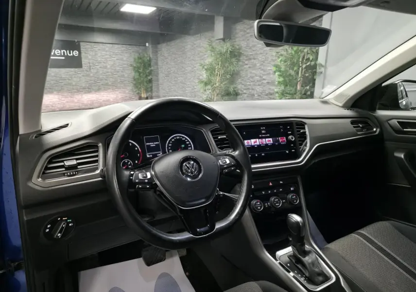 Intérieur du Volkswagen T-Roc bleu foncé, vue côté conducteur, volant cuir multifonction et tableau de bord digital.
