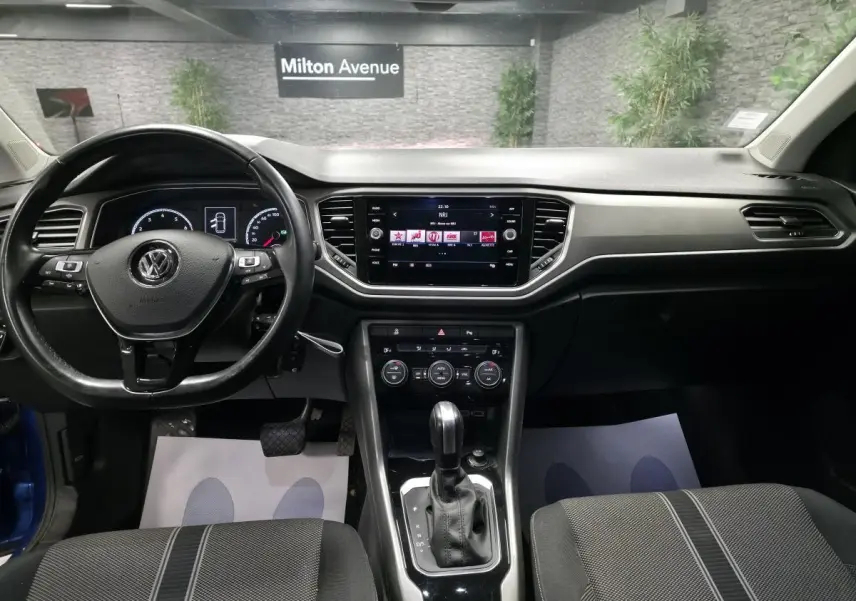 Vue intérieure avant du Volkswagen T-Roc 1.5 TSI Evo 2020, tableau de bord noir avec écran tactile central et volant multifonction.