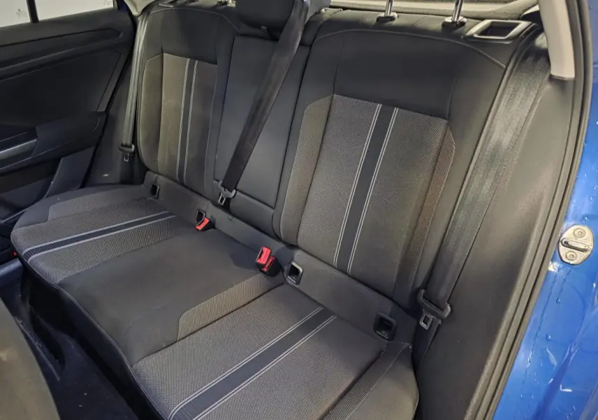 Vue intérieure du siège arrière côté droit du Volkswagen T-Roc bleu foncé, avec ceintures de sécurité et tissu noir à motifs gris.