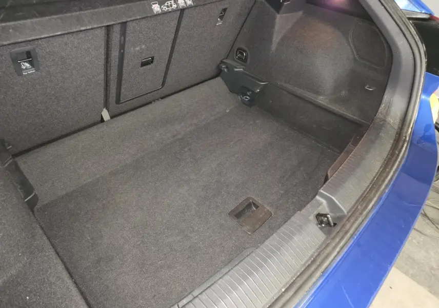 Vue intérieure du coffre spacieux d'un Volkswagen T-Roc bleu foncé, montrant la moquette noire et les fixations ISOFIX.
