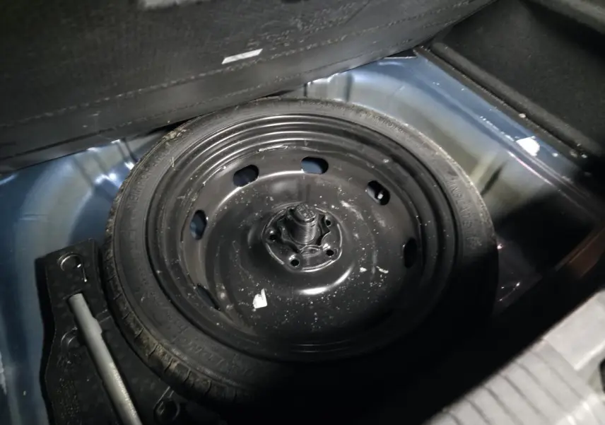 Gros plan sur la roue de secours noire dans le coffre bleu foncé du Volkswagen T-Roc 1.5 TSI Evo 2020.