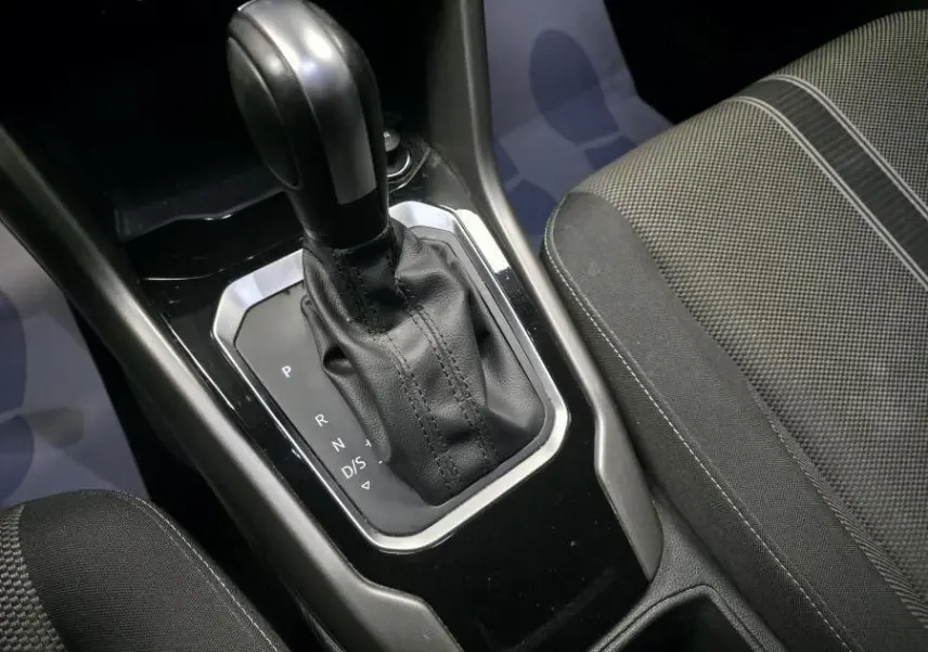 Gros plan sur le levier de vitesses automatique noir et cuir du Volkswagen T-Roc 1.5 TSI Evo Lounge, intérieur tissu gris.