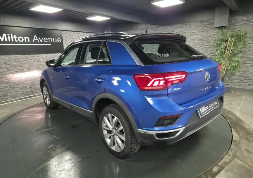 Volkswagen T-Roc bleu foncé en 3/4 arrière droit, avec jantes alliage argent et toit noir contrasté.