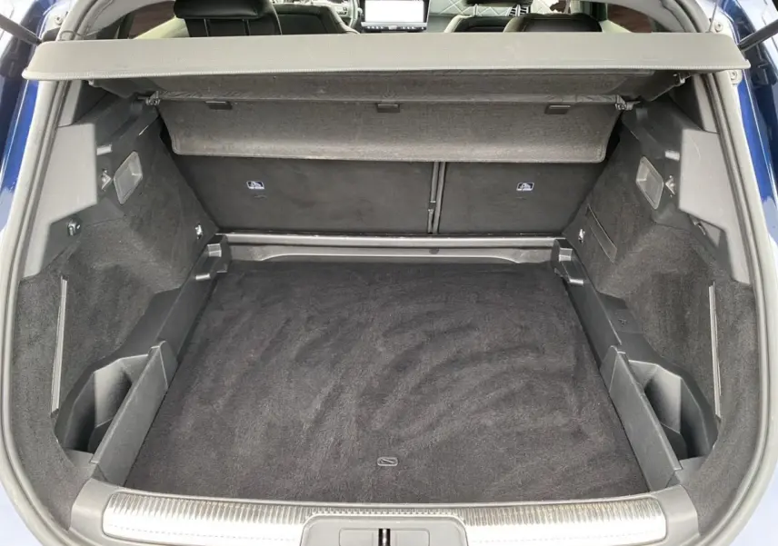 Coffre ouvert vu de l'arrière d'un DS7 Crossback bleu 2024, avec tapis noir et cache-bagages déployé.