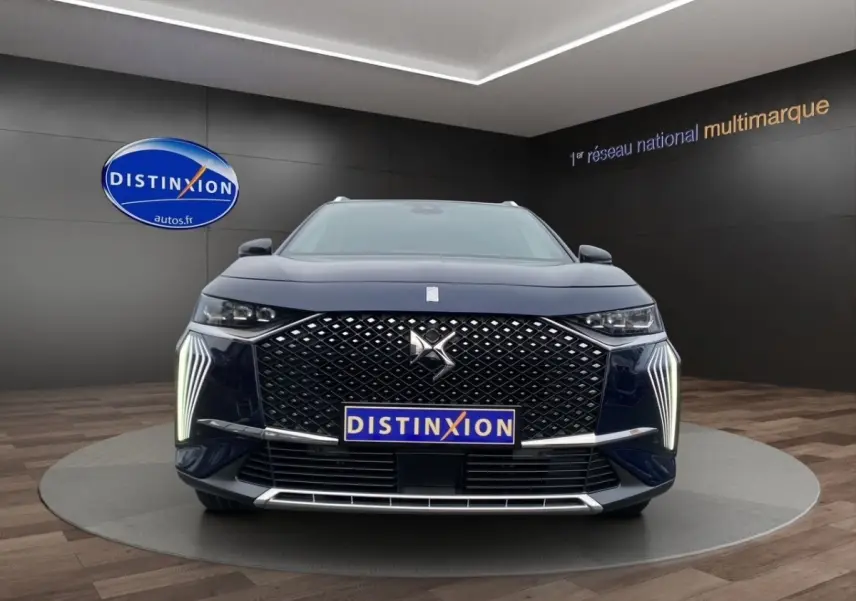 Vue frontale du DS7 Crossback bleu 2024 avec calandre distinctive et feux LED verticaux allumés.