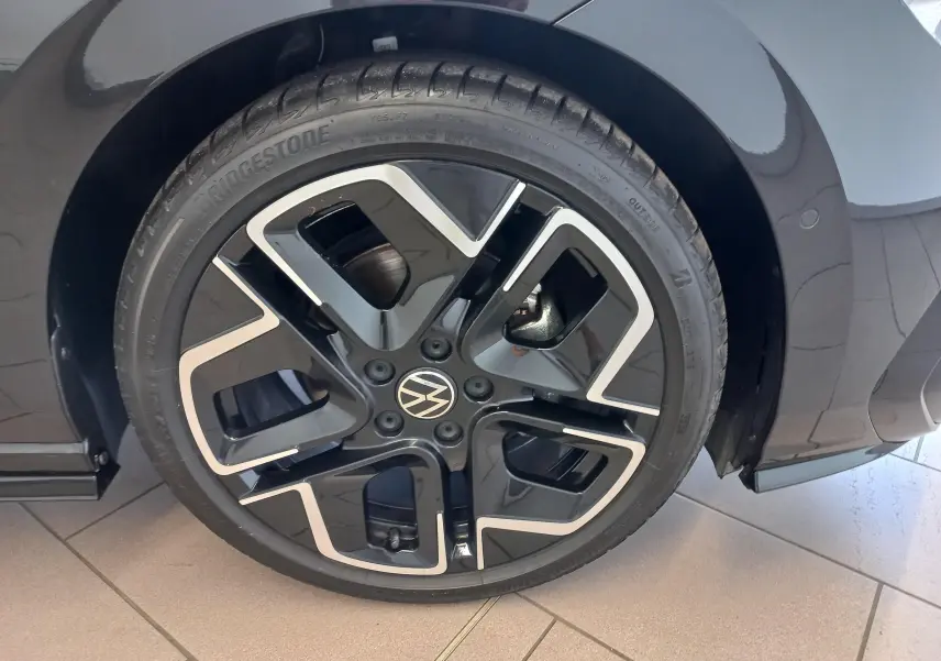 Gros plan sur la roue avant droite d'une Volkswagen Golf 1.5 eTSI R-Line noire avec jante alliage noire et argent.