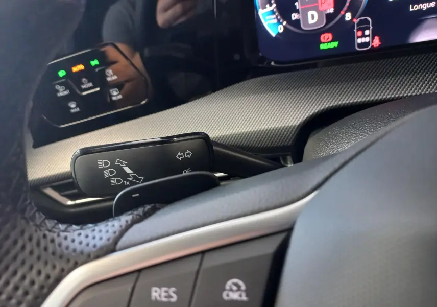 Vue rapprochée du combiné d'instruments et des commandes au volant du Volkswagen Golf 1.5 eTSI noir Ebène, avec affichage numérique.