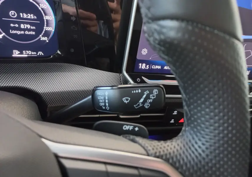 Gros plan intérieur sur le commodo d’essuie-glace et le tableau de bord numérique d’une Volkswagen Golf 1.5 eTSI noire.